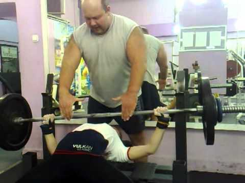 Марьяна выполняет жим лежа под руководством отца