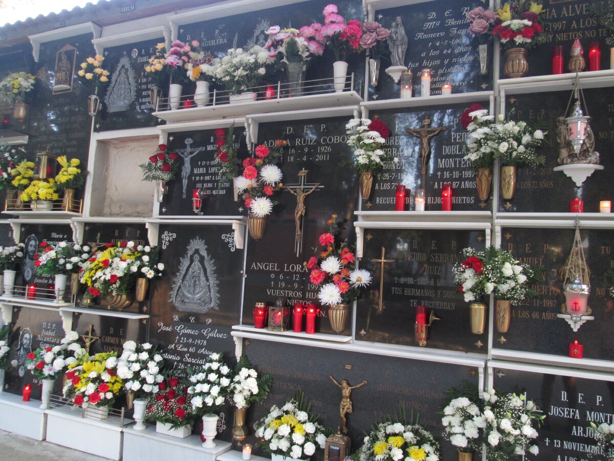 Цветы и горящие свечи украшают каждую занятую ячейку на кладбище