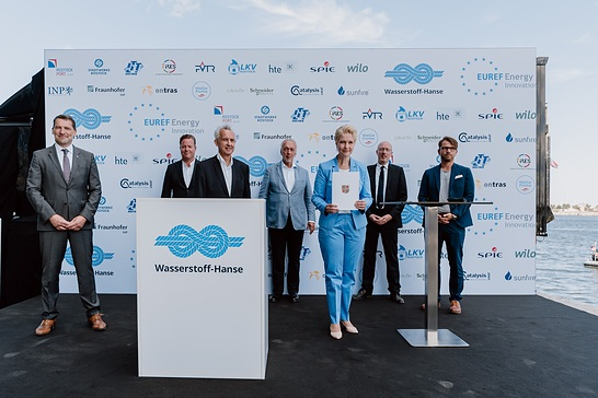 (слева направо) Подписавшие декларацию о создании «Wasserstoff-Hanse»: Йенс Шарнер (директор порта Росток), Оливер Хермес (президент и генеральный директор Wilo Group), Райнхард Хюттль (научный директор и управляющий директор EUREF Energy Innovation GmbH), Райнхард Мюллер (президент EUREF AG), Мануэла Швезиг (министр-президент Мекленбурга - Передней Померании), Кристиан Пегель (министр энергетики, инфраструктуры и цифровизации Мекленбурга - Передней Померании), Кнут Шефер (управляющий директор Weissen Flotte GmbH) Copyright: EUREF / Мелани Вернер