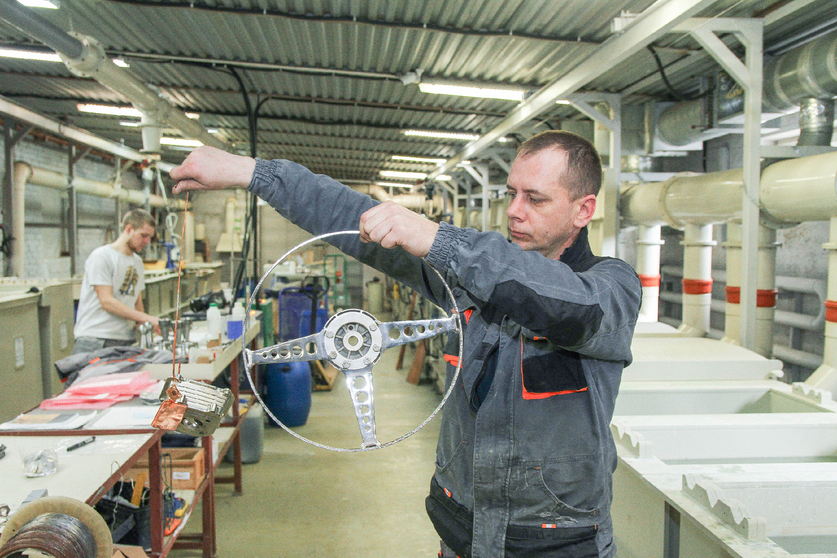 Рабочий держит руль от раритетного автомобиля "Ford"