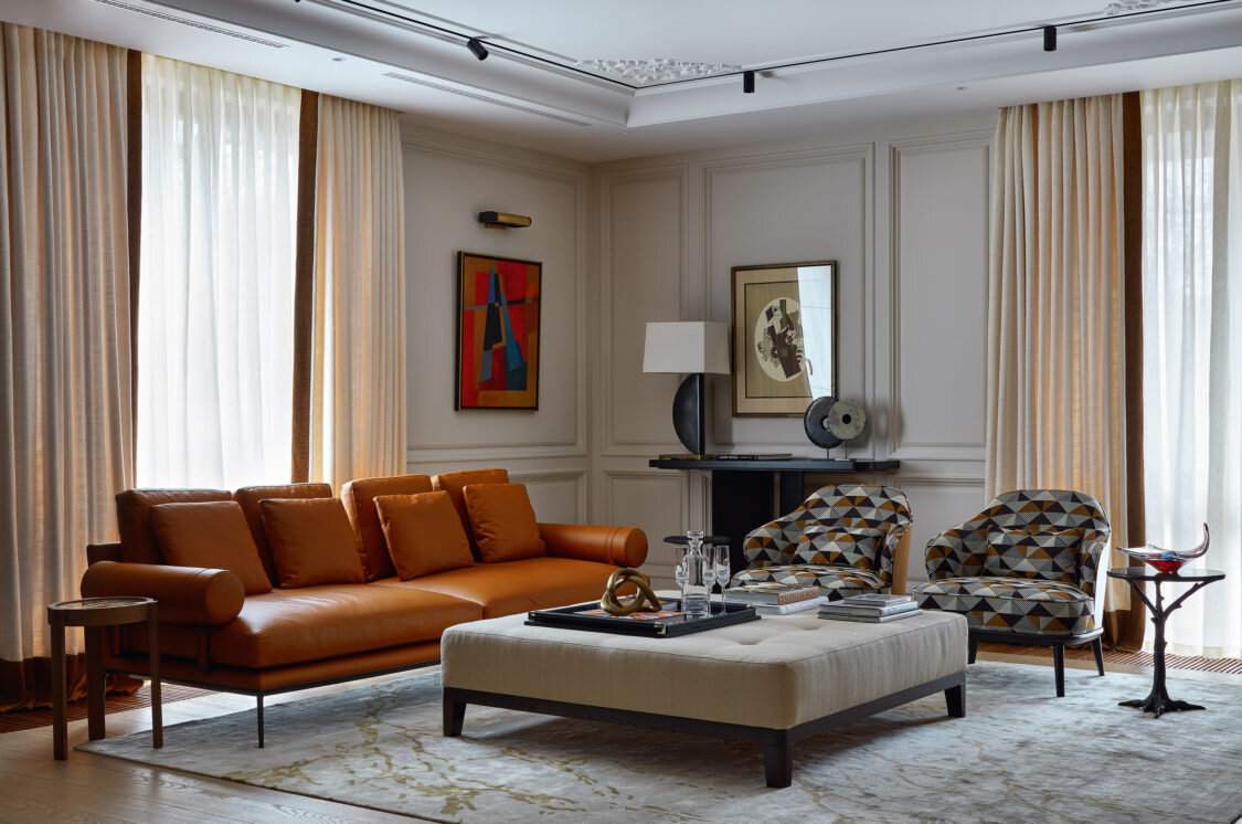 Гостиная. Диван, B&B Italia; кресла, Horus, в обивке из ткани, Misia; пуф, Gaisin & Co, в обивке из ткани, Dedar; из нее же сшиты шторы. На консоли по дизайну Полины Пидцан лампа, Theodore Alexander. Аксессуары, Standart Interiors. На стене картина Николая Бирюкова “Закат в порту” 2001 года и литография из парижской галереи Maeght.