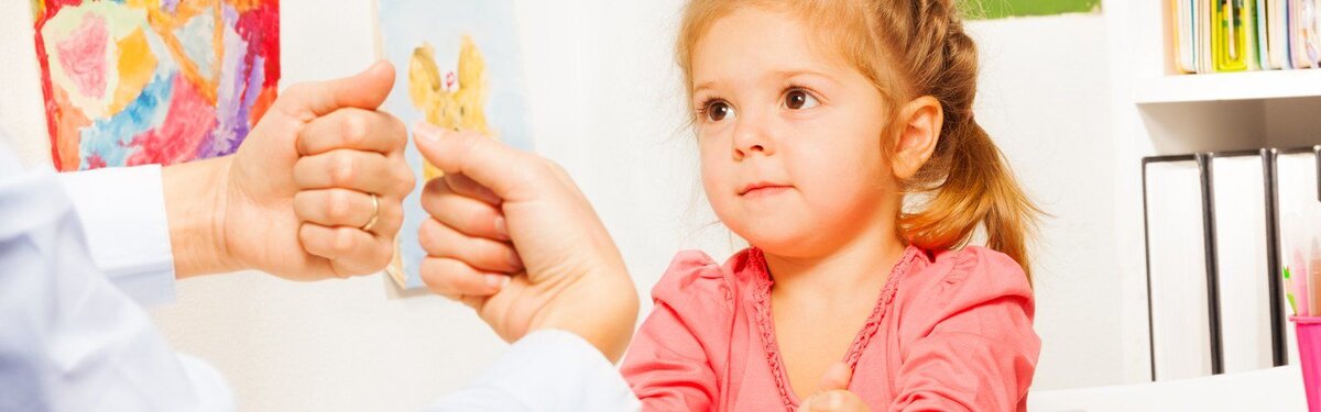 Девочке показывают упражнения на развитие мелкой моторики