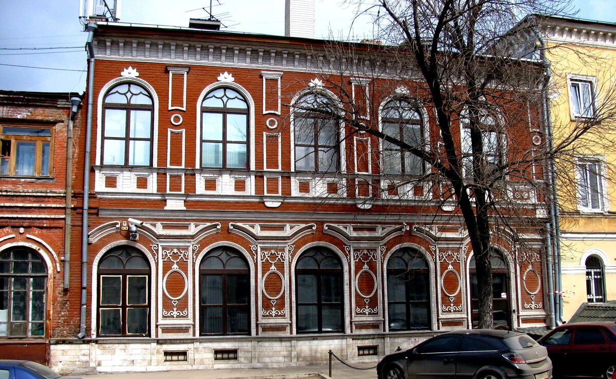 Неоштукатуренные стены здания окрашены в красный цвет, лепной декор выделен белым