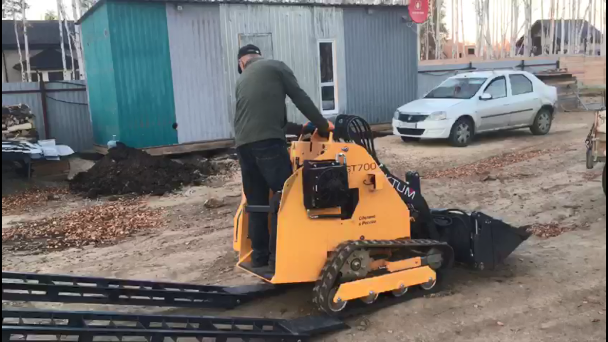 Модель мини-погрузчика GT700 производства DIKTUM с навесным оборудованием "Ковш 4в1" и дополнительной комплектацией "Сходни"