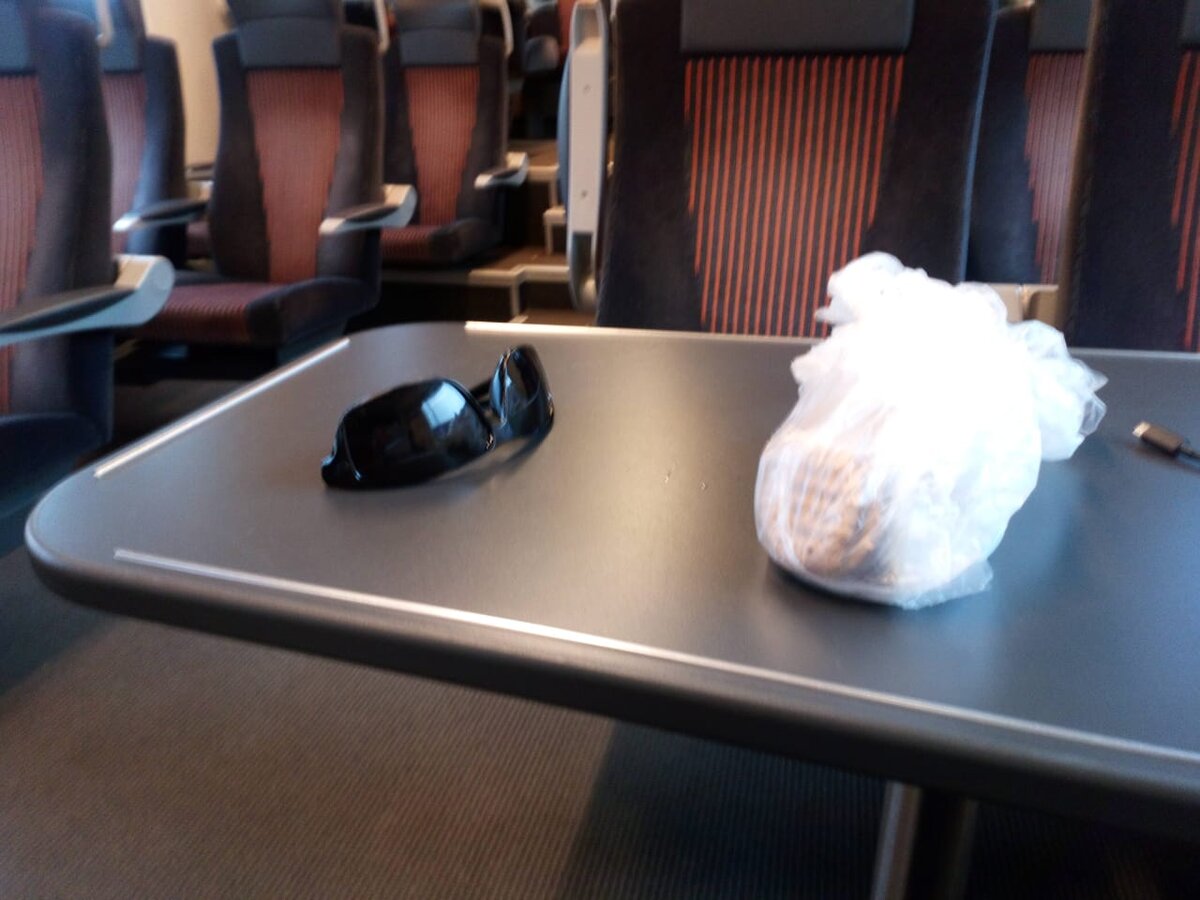 Поезд. Еду из Нарвы в Таллин. Мои очки, в пакете еда. И видно слева кусочек провода, зарядный шнур для моего смартфона Sony.