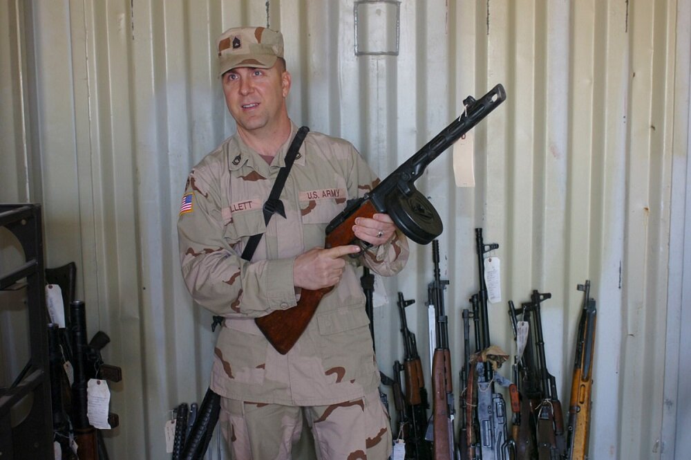 Американский военнослужащий демонстрирует захваченный ППШ-41. На фоне другого трофейного оружия.
