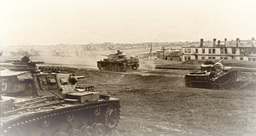 Утро 15 сентября, танки PzKpfw III группы «Эдельсхайм» выехали к железной дороге для атаки в направлении Максимовского разъезда. Здание справа уже выгорело в результате обстрела этого места реактивными минометами. Несмотря на повреждения, этот дом сохранился до сих пор, современный адрес — ул. Автотранспортная, 1. 
