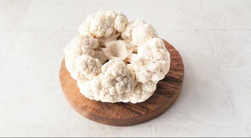 Переверните кочан цветной капусты кочерыжкой вверх и вырежьте часть кочерыжки