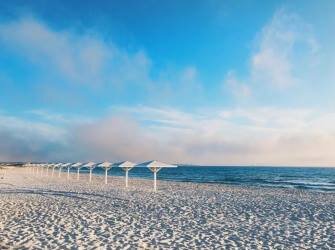 Район Крыма, где находится пляж, отличается жаркой и засушливой погодой в летний период. По этой причине в разгар сезона температура воды в море может подниматься до +28C°. Спрятаться от солнца стоит под зонтиками, которые можно снять напрокат в специальном пункте. Там же можно на несколько часов арендовать шезлонги. Вдоль большей части береговой полосы стоят раздевалки и душ, где можно бесплатно смыть с себя морскую воду.