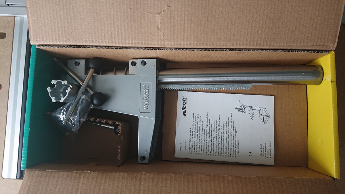 Внутри База для дрели, установленная на полированный стержень. База и зубчатая рейка выполнены из алюминиевого сплава, база дополнительно окрашена в серый цвет.