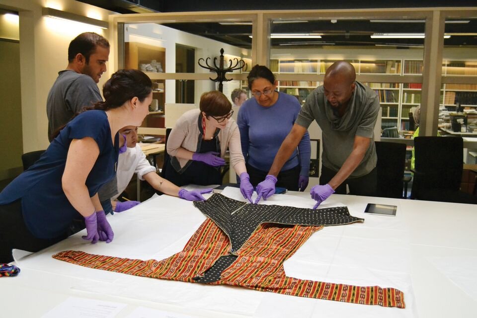 Collections officer Abigael Flack shows volunteers in Oxford a textile from Syria Tammam Aboukerech