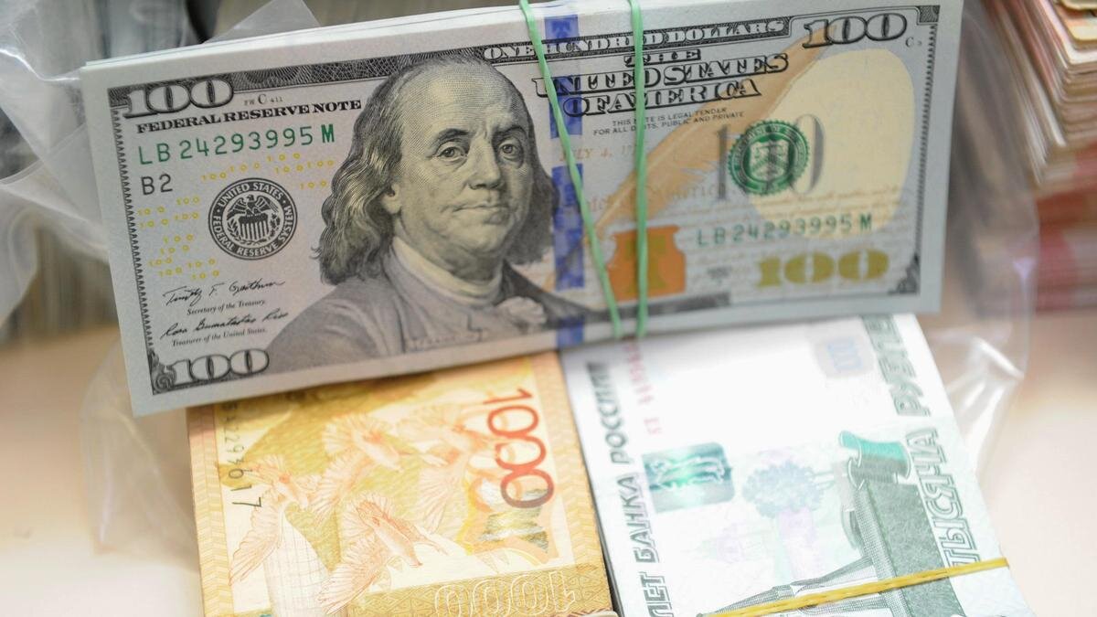    Пачка долларов лежит на пачках тенге и рублей:NUR.KZ/Владимир Третьяков