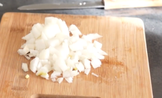 Залить воду в кастрюлю, добавить куриные кубики и дождаться закипания. Репчатый лук почистить и порезать на небольшие кусочки.