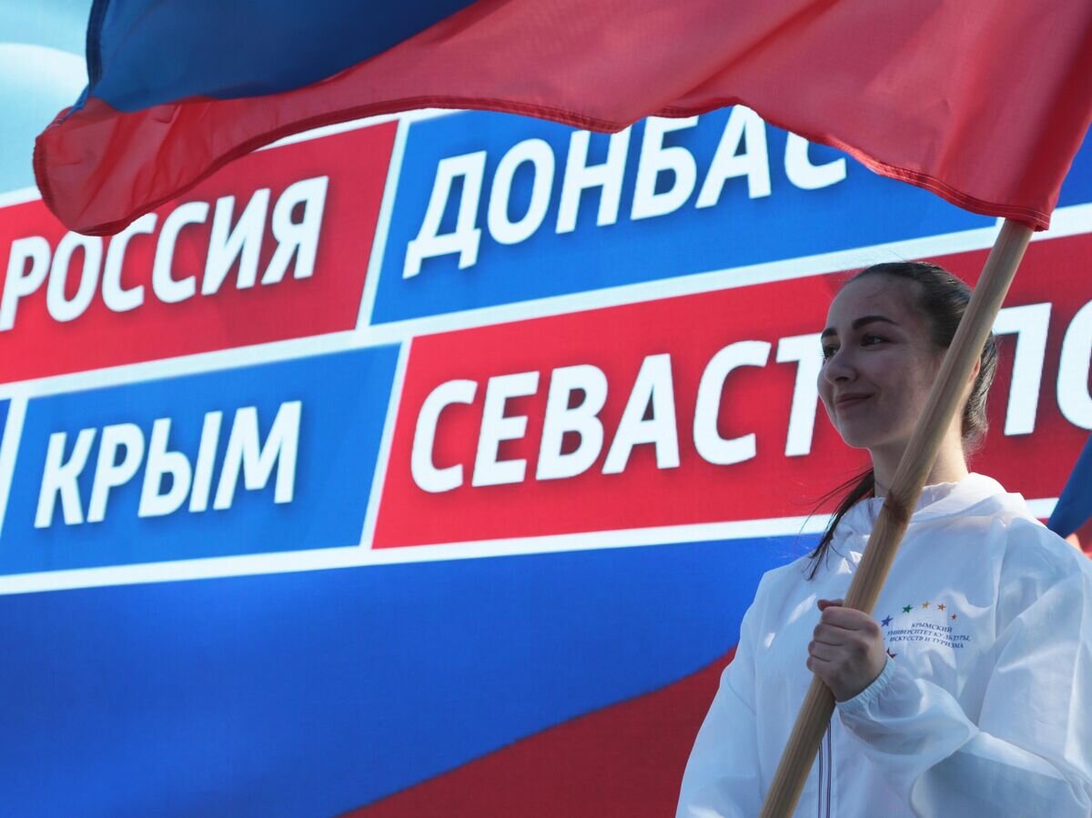    Девушка держит в руках флаг на праздничном митинге в честь восьмилетия провозглашения ДНР и ЛНР© РИА Новости / Макс Ветров