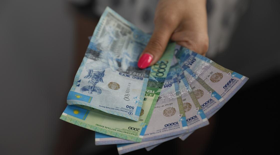    Женщина держит минимальную зарплату в РК:NUR.KZ / Петр Карандашов