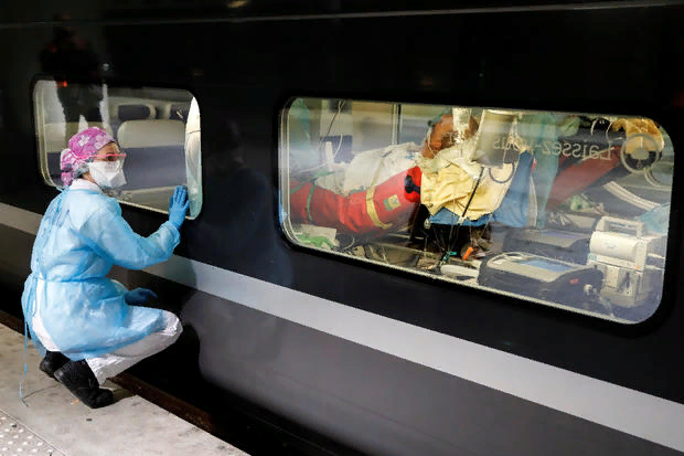 Медицинский персонал просматривает окно высокоскоростного поезда TGV перед его отправлением, чтобы эвакуировать пациентов, инфицированных COVID-19, из больниц региона Париж в Бретань, поскольку распространение коронавирусной болезни продолжается, в Париже, Франция, 1 апреля 2020 года.