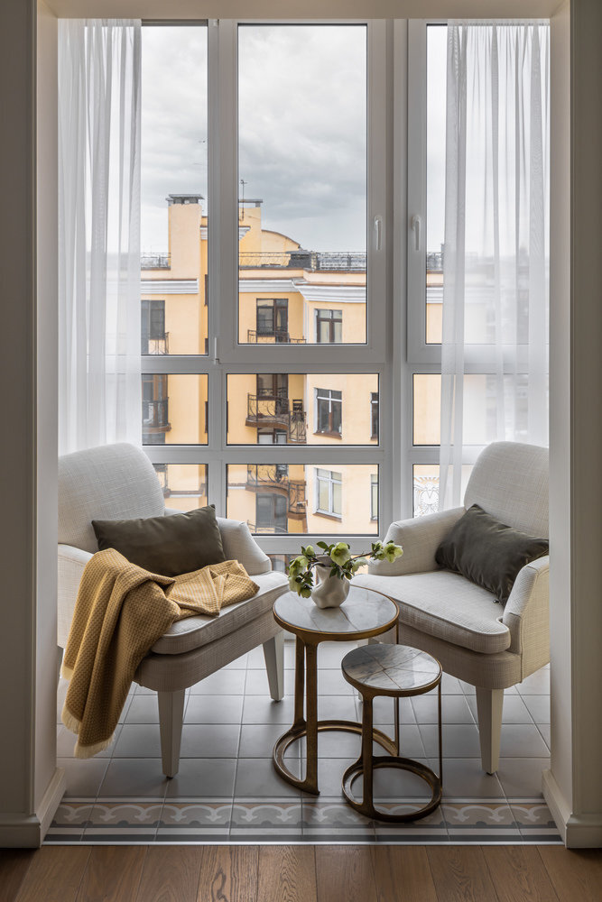 Лоджию присоединили к комнате и зонировали другим напольным покрытием — плиткой. Здесь организовали зону отдыха. Радиатор отопления вынесли на стену рядом с балконным проёмом и упаковали в нишу, кондиционер — там же. Чтобы нивелировать значимость техники, предусмотрели несколько открытых полок для декора.