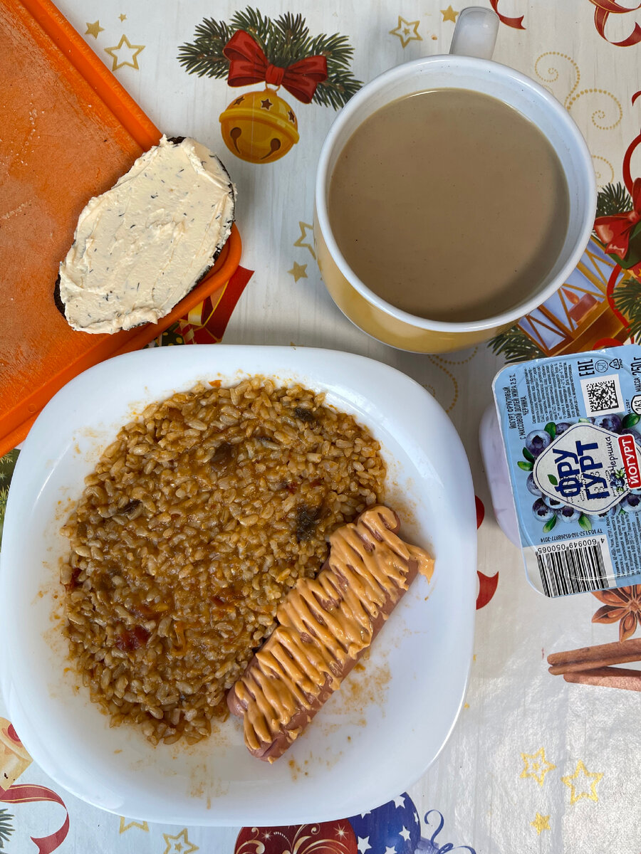 Кофе, йогурт, бутерброд с творожным сыром, рис с овощами и пара сосисок, политые соусом.