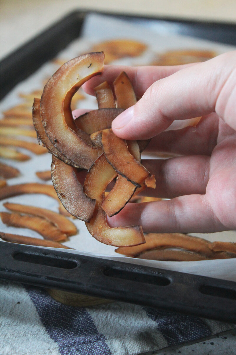 Кокос почистить,нарезать овощерезкой на полосочки, выложить на пергамент и на противень.
Убрать в духовку, выпекать при 100° 40 минут. Готово .