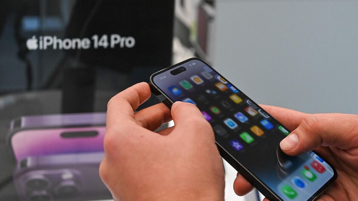    Покупатель держит в руках телефон компании Apple в магазине re:Store на Тверской улице в Москве© РИА Новости / Евгений Одиноков
