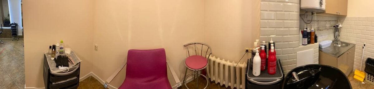 панорама с рабочего места. на розовом стуле сидит клиент, а справа мойка для парикмахеров.