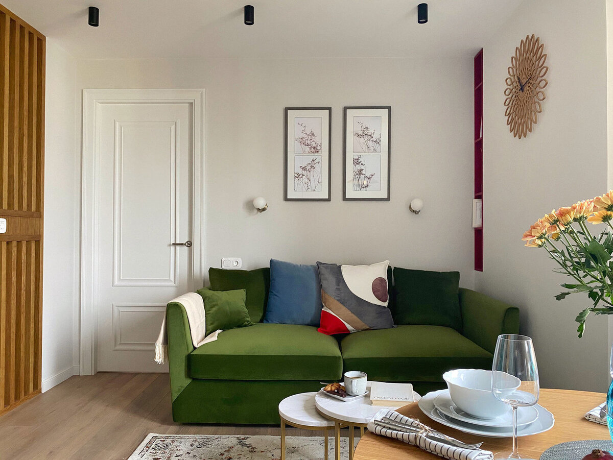 Небольшую зону гостиной обозначили ковром. Светлую отделку разбавили яркими акцентами —травянисто-зелёным диваном и красной нишей в стене. Проект дизайн-студии ONE LINE.