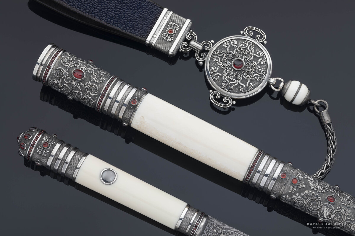 Автор: Жигжит Баясхаланов. Эксклюзивный бурятский традиционный нож "Пламя костра".
Материалы: Дамасская сталь, моржовый клык, бронза с гальваническим серебрением/белый металл, кожа ската, гранаты. Сайт автора: zhigzhit.com