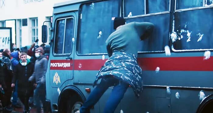 Требующее "свободы" "оно же дитя" пытается в прыжке высадить локтем стекло автобуса Росгвардии. Кадр из видео массовых протестов в Москве в начале 2021 года. 