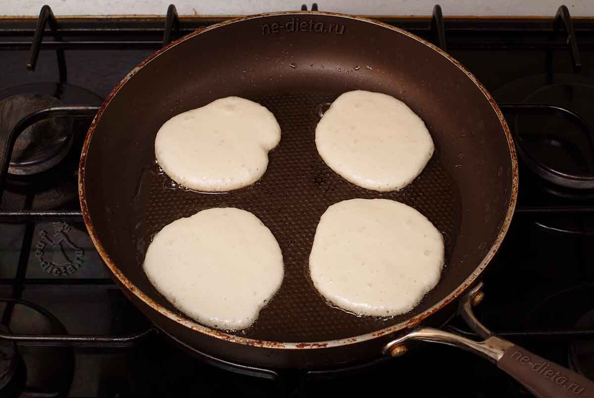 1. Для того чтобы приготовить самые пышные оладьи на кефире с добавлением соды, в кастрюлю надо налить кефир и воду и нагреть эту смесь на медленном огне до теплого состояния (не более 40 — 50 градусов).
2. Яйцо взбить с сахаром и солью с помощью миксера, хотя как и в других случаях, наличие кухонной техники не является обязательным условием для приготовления этих оладий, так как тесто для них вполне можно замешать вилкой или ручным венчиком.
3. В яйцо влить теплый кефир и взбить эту смесь до образования легкой пены.
4. Постепенно всыпать просеянную муку, параллельно вымешивая тесто, чтобы оно становилось гладким и однородным.
5. В конце приготовления всыпать соду, причем в данном случае ее можно предварительно не гасить, поскольку она погасится уже в тесте под действием кислоты кефира.
6. В последний раз все как следует перемешать миксером и в результате получится густое тесто для пышных оладий на кефире.
7. Большую сковороду как следует разогреть и налить в нее приличное количество рафинированного растительного масла, после чего ложкой аккуратно выложить на нее тесто, придавая ему форму небольших круглых оладий. Вначале они будут выглядеть подозрительно плоскими, однако в процессе жарки на среднем огне прямо на глазах станут увеличиваться в толщину и превращаться в аппетитные пышные лепешки.
8. Жарить оладьи нужно сначала на достаточно сильном огне с двух сторон до образования румяной корочки, после чего огонь можно убавить и в течение пары минут довести эту выпечку до полной готовности. Затем оладьи надо снять на сервировочное блюдо, а сковороду снова разогреть, после чего подлить на нее немного масла и выложить следующую порцию теста.