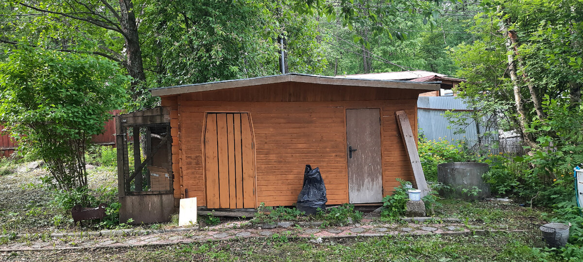 Правая серая дверь ведет в помещение санузла, которое по сути есть обшитый деревом вагон, левая желтая дверь из досок в дровник. К хозблоку пару лет назад был пристроен вольер, так как до недавнего времени у меня жила ворона и я брала ее летом на дачу. Теперь туда переедут дрова, а помещение будет использоваться под всякие грабли-лейки.
