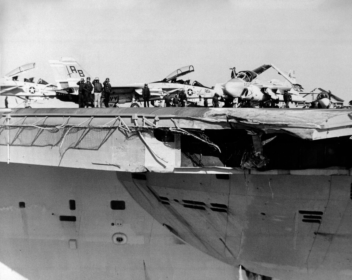 Повреждения авианосца. Источник https://upload.wikimedia.org/wikipedia/commons/b/be/DN-SN-87-07322_USS_John_F._Kennedy_damaged_front_end_of_angled_deck.jpeg