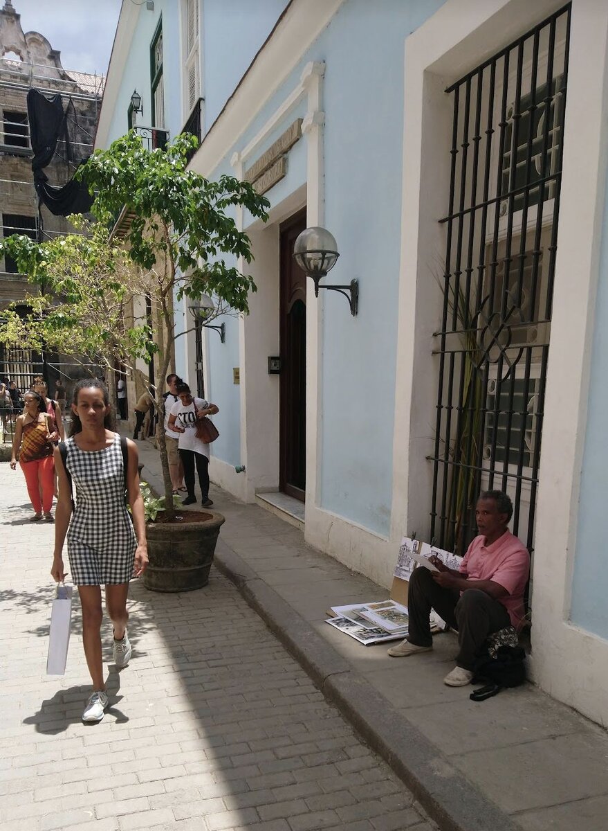 Обычная улочка Гаваны посреди рабочего дня. Банковские клерки закрывают отделение, уличный художник работает в тени, служащие детского сада и домохозяйки спешат на обед. 