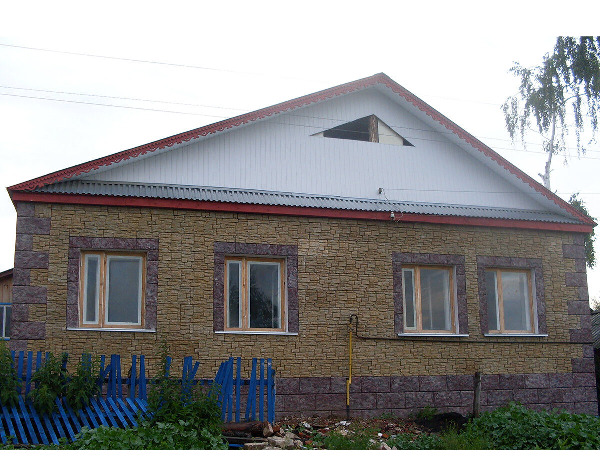 Обшивка фасада частного дома бетонными панелями под натуральный камень