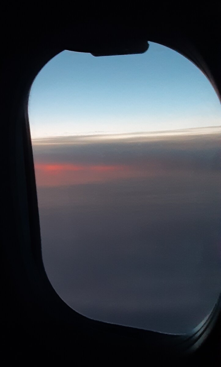 Закат с высоты полёта на самолёте. Вид из окна иллюминатора.