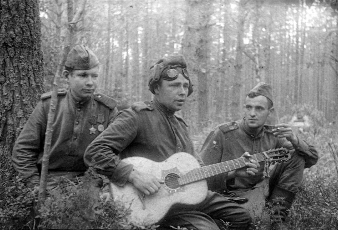 Советские бойцы слушают своего товарища, играющего на гитаре. 1-й Белорусский фронт. 1944 г. Автор: Иван Нарциссов.