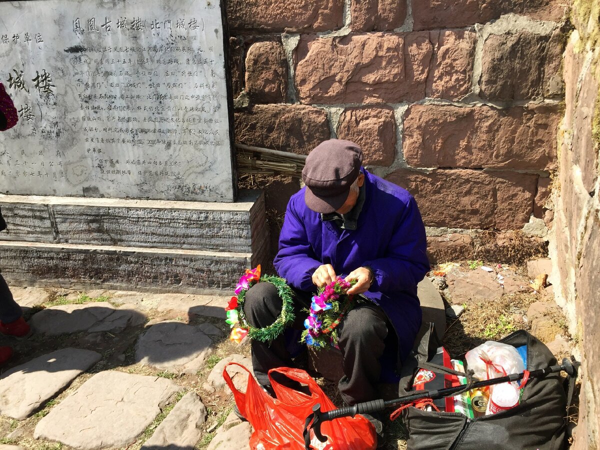 Так местные китайские пенсионеры зарабатывают лишнюю копейку на туристах. Например, делают веночек 