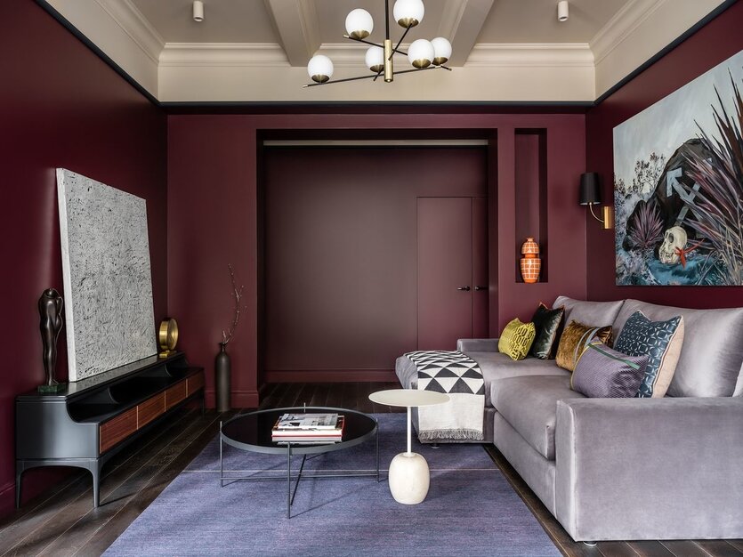Гостиная. Краска на стенах — Farrow&Ball (No. 222, Brinjal), на потолке — Farrow&Ball (No. 264, Oxford Stone). Диван, Geniuspark. Столики, торшер, L'appartement. Бра, Faro. На комоде — картина «Off White» Федоров Константин, «Rooma design»; над диваном — картина «Приобретенная беспомощность 2, Кирилл Басалаев, L'appartement. Декоративные подушки, Enere. Межкомнатные двери, Neogreen