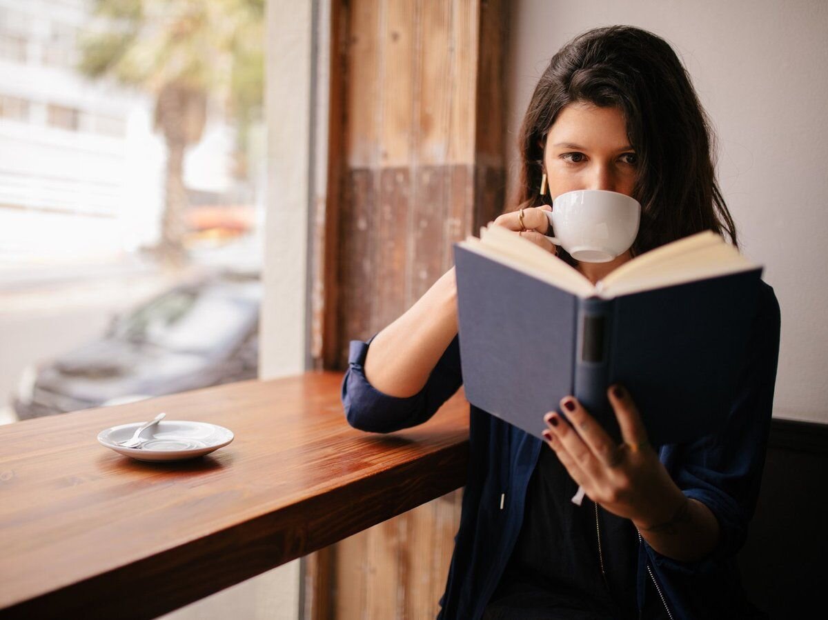 Read booking. Девушка с книгой. Девушка в кафе с книгой. Чтение в кофейне. Женщина читает.