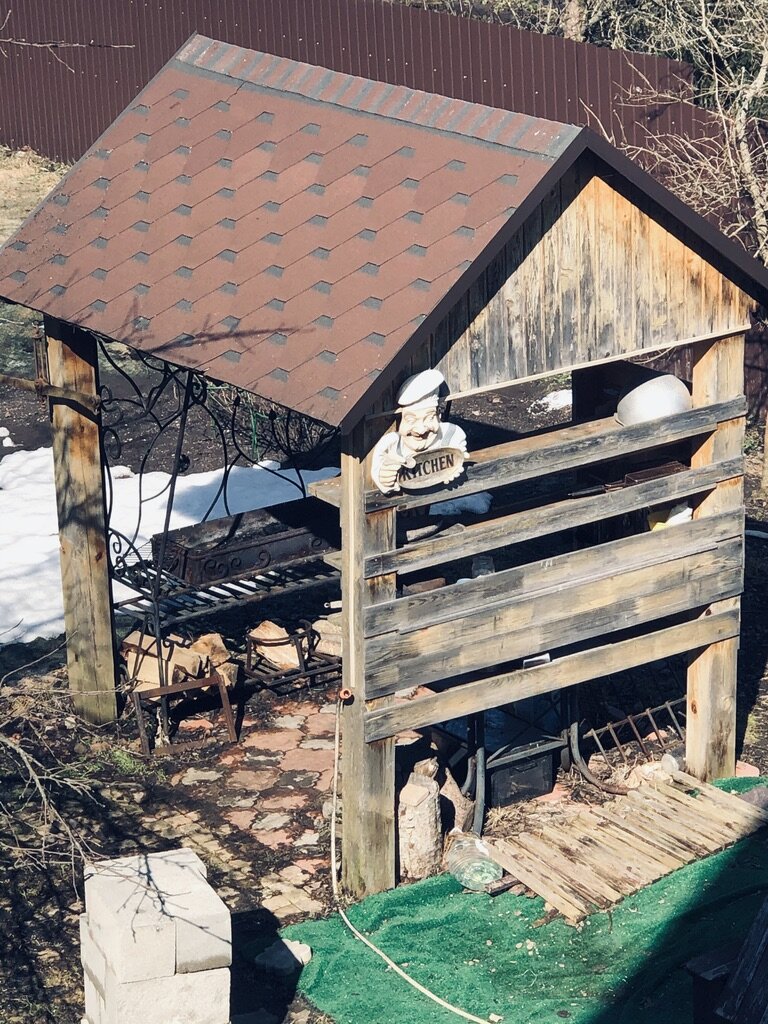 Наша мангальная. Мы хотели ее просто покрасить и забить доски до земли, но придется ее ломать и строить новую. Видно, что деревянные опорные столбы начали крениться. Фото автора. 