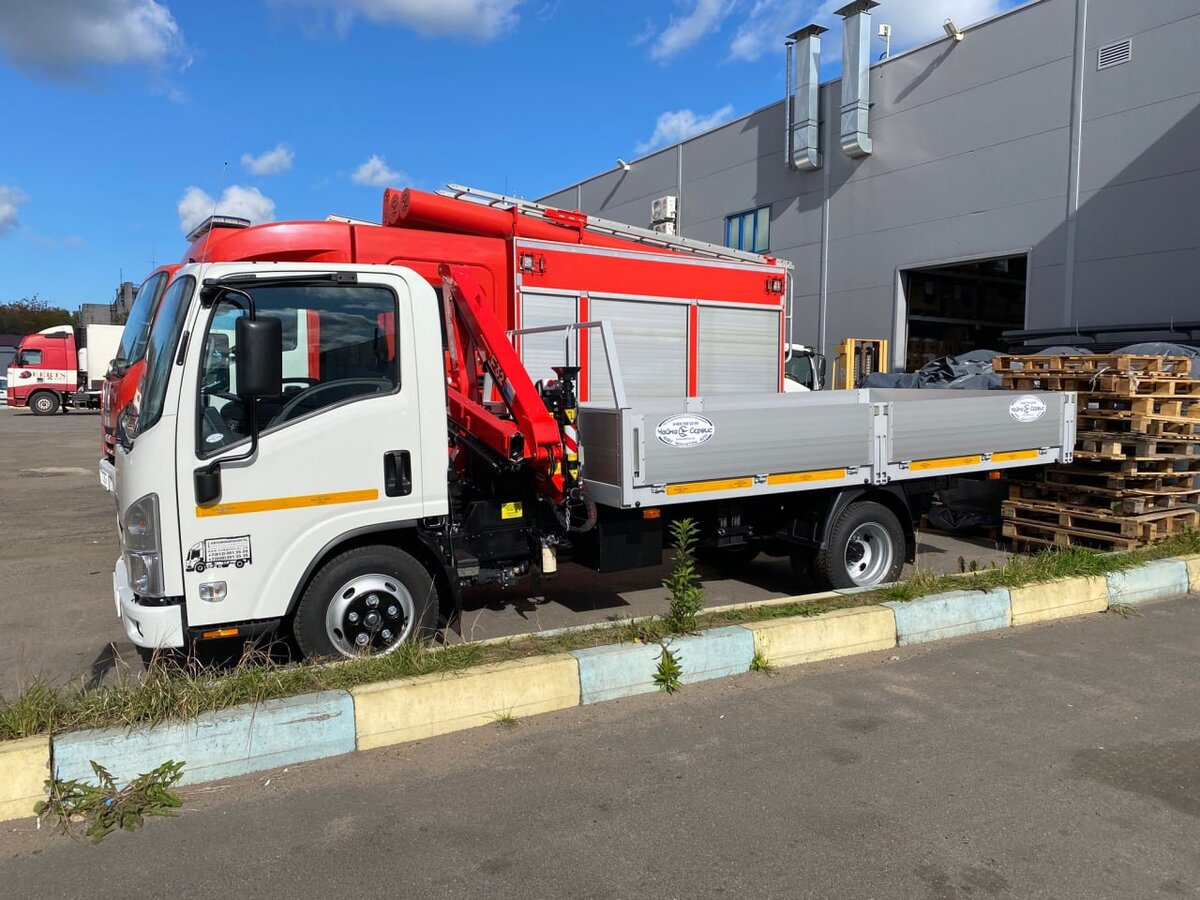 Isuzu NMR с КМУ и бортовой платформой. Наглядно видна компактность грузовика – особенно по сравнению с пожарной машиной рядом.