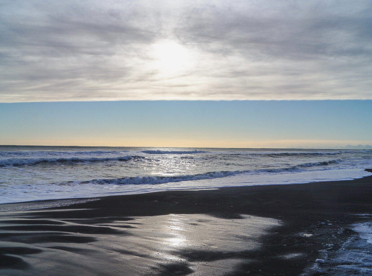 Солнце отражается в черном песке