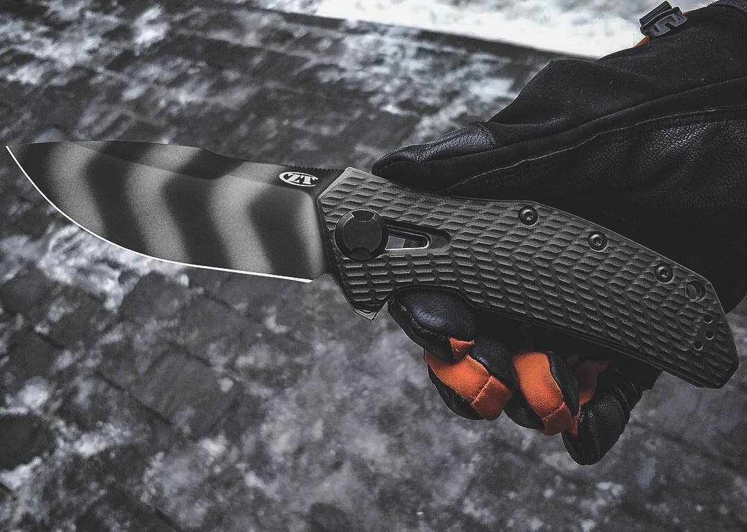 Нож ZT 0308BLKTS. Премиальная сталь CPM 20CV обеспечивает особую твердость, износостойкость и удержание кромок; финишная обработка Блэк Вош Финиш с тактическими полосками tiger stripes.