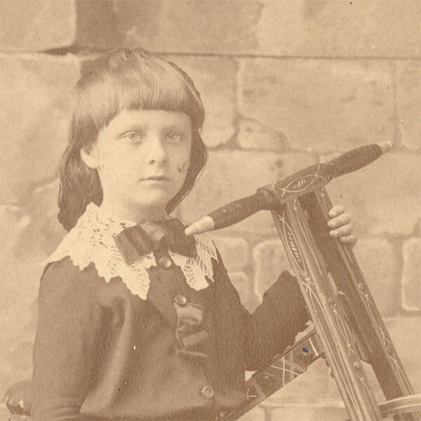 Фотография 1880-х годов из коллекции Веломузея Андрея Мятиева, на которой запечатлены девочка и архаичный трёхколесный велосипед.