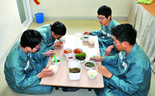 Заключённые на обеде. Белый цвет нашивок указывает на квалификацию преступников как «обычные». То есть, не тяжкие преступления. 
