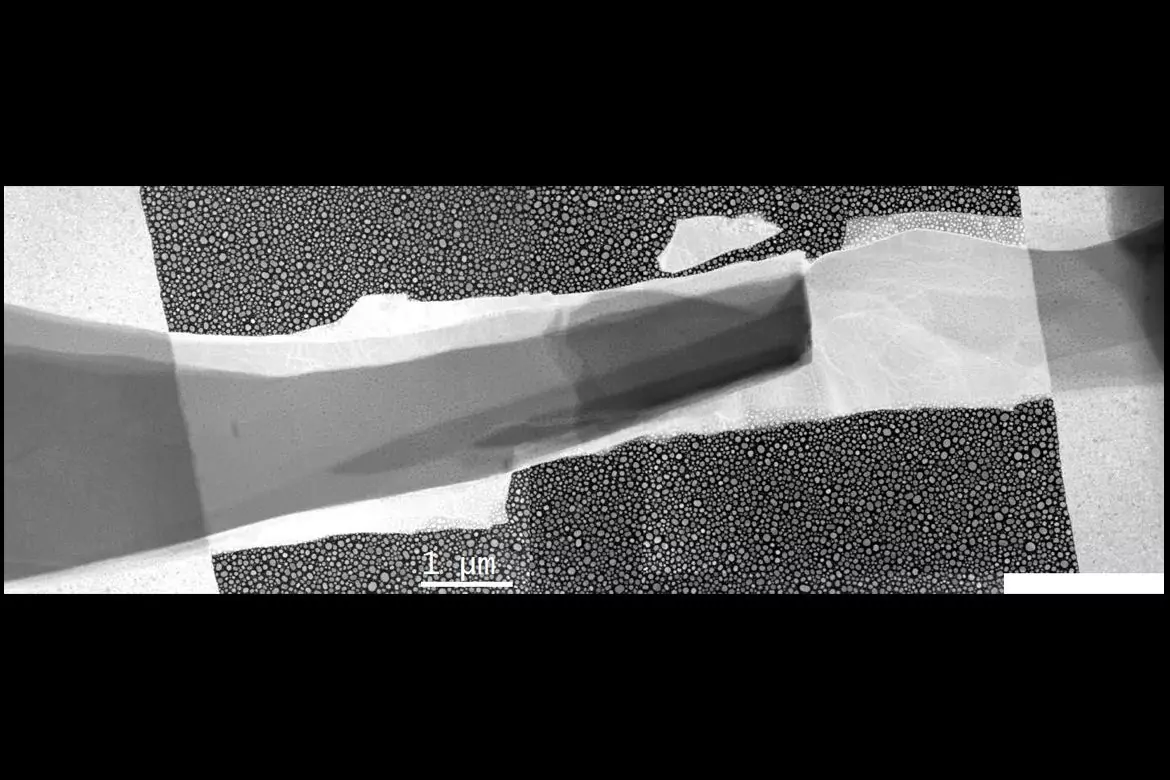 Это изображение, полученное с помощью электронного микроскопа, показывает два перекрывающихся полупроводника в темной области посередине. Здесь происходит большая часть охлаждения. Маленькие «точки» - это наночастицы индия, которые использовались в качестве «термометров». 
