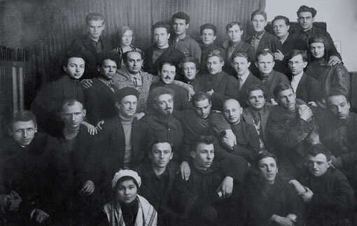 Писатели — члены Московской ассоциации пролетарских писателей (МАПП). Первый ряд (слева направо): 1. О. Грудская; 2. Неизв.; 3. Неизв.; 4. П.Г. Скосырев. Второй ряд: 1. А.П. Селивановский; 2. И.С. Макарьев; 3. В.П. Ставский; 4. Ю.Н. Либединский; 5. В.М. Киршон; 6. Л.Л. Авербах; 7. Ф.И. Панфёров; 8. А.А. Фадеев; 9. Н.М. Буачидзе. Третий ряд: 1. А.А. Исбах; 2. Неизв.; 3. Бела Иллеш; 4. Мате Залка; 5. В.В. Ермилов; 6. А.А. Сурков; 7. Г.М. Корабельников; 8. А.Н. Афиногенов. Четвёртый ряд: 1. Неизв.; 2. О.Ф. Берггольц; 3. Фридман; 4. Неизв.; 5. А.А. Боровой; 6. С.Л. Кирьянов; 7. Неизв.; 8. Неизв.; 9. Неизв. Фото © Wikipedia