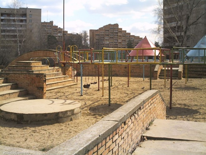 1) «Спортивный городок» (N 54° 52.627′, E 37° 12.828′) – прекрасная детская площадка, почти ровесник самого города. Своего рода – небольшой «Диснейленд» для детей. А сколько приятных воспоминаний об этом месте возникает у тех, кто провёл своё детство в Протвино! Какому ребёнку не хочется забраться повыше, посоревноваться со сверстниками? А тут как раз всё, что нужно для этого. (* Есть в Протвино спортивные сооружения не только для детей. Весь город буквально усыпан хоккейными коробками и площадками для тенниса. И есть, конечно, свой – взрослый спортивный городок. Он находится недалеко от Дворца спорта. Перед самим Дворцом спорта установлен необычный флюгер – советую взглянуть.)
В то время, пока Ваш ребёнок играет с другими, советую обратить внимание на «башни». Что за «башни»? — ничего такого вокруг не видно! 