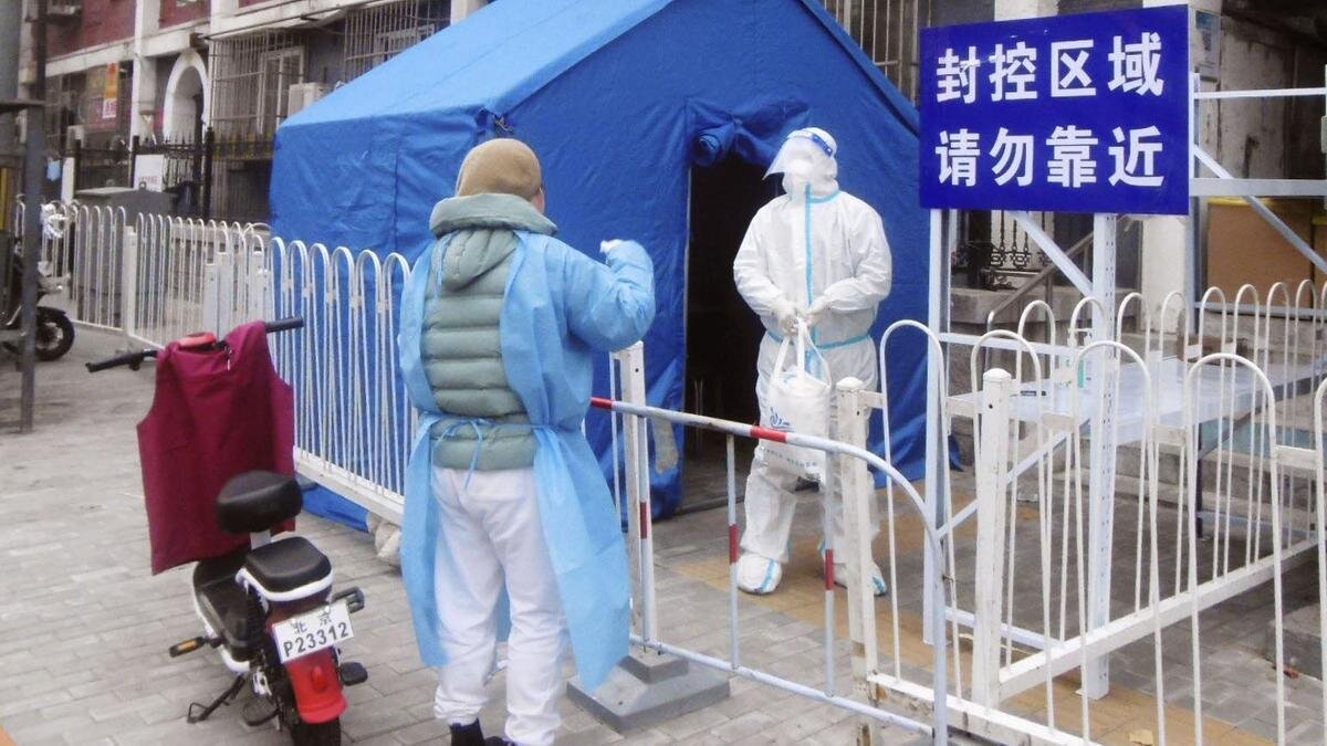    Человек в защитном костюме от коронавируса стоит перед палаткой:Kyodo News via Getty Images