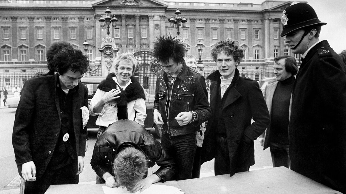 Sex Pistols, подписывают новый контракт на запись с A&M Records возле Букингемского дворца в 1977 году. Макларен стоит по левую руку Сида Вишеса (в проклепанной косухе). 