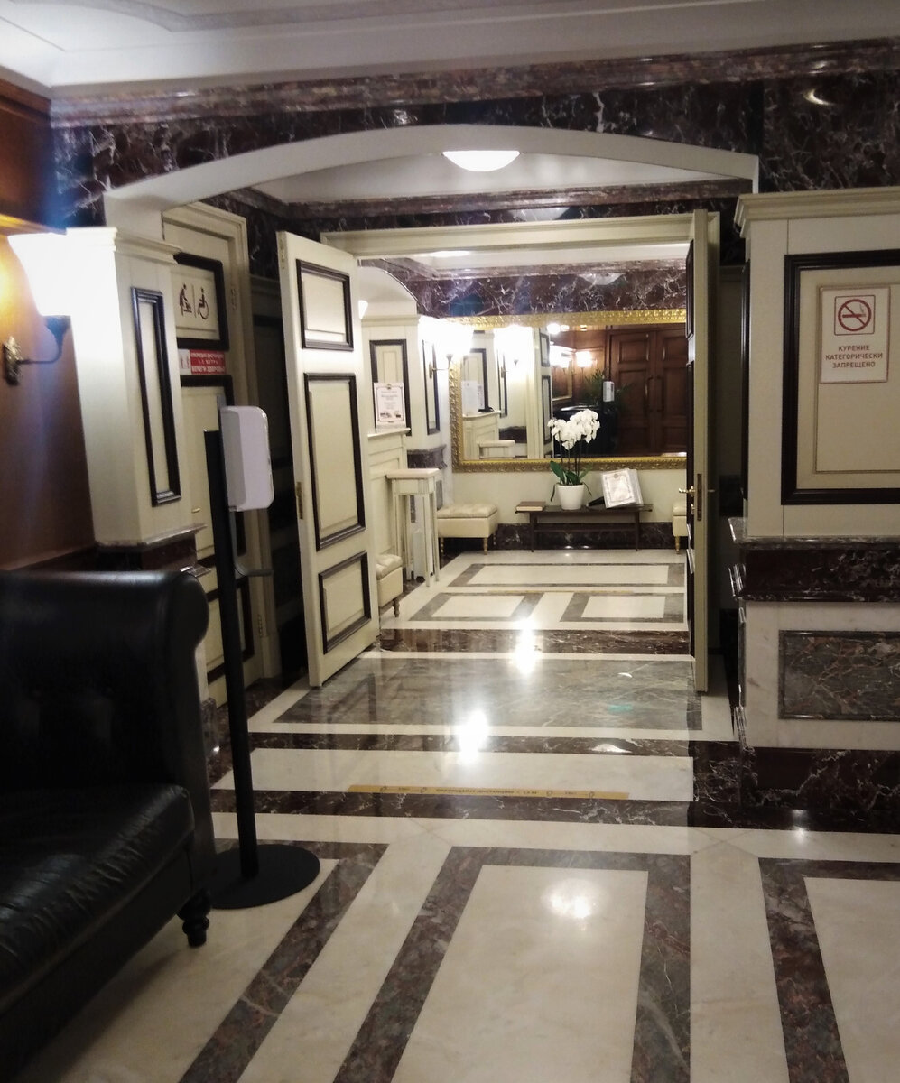 Так выглядит главный вход - мягкий кожаный диван на входе, живые орхидеи под золоченным зеркалом.